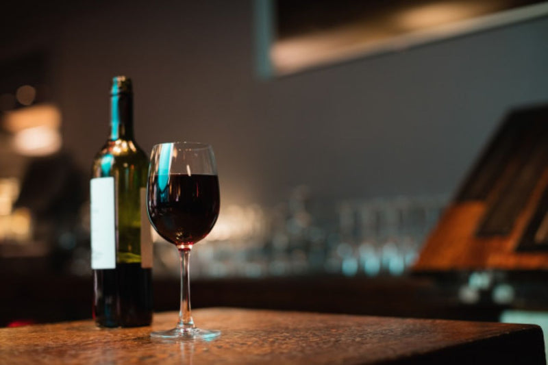 Red wine bottle and wine glass on a table
